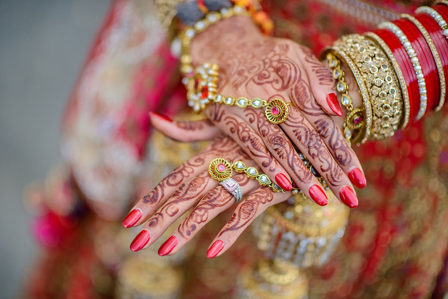 Close-up details of traditional Indian bridal jewelry and henna-decorated hands.