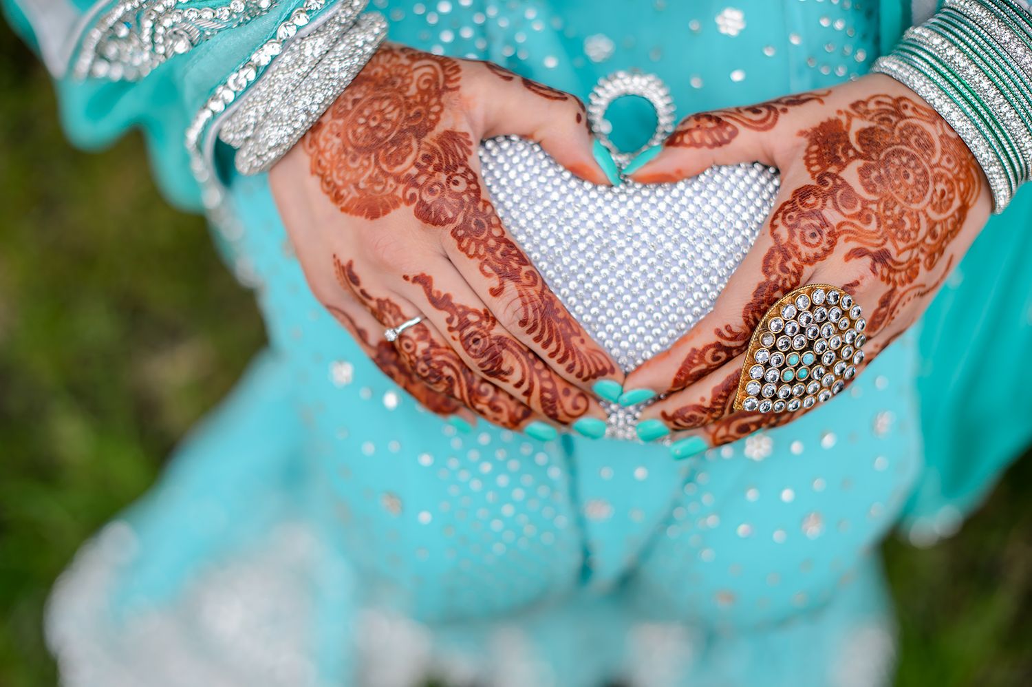 Decorated hands with henna designs holding traditional Indian wedding jewelry.