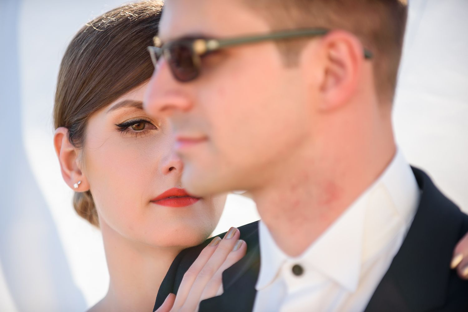 Stylish wedding couple photographed against bright sunlight in an urban setting.