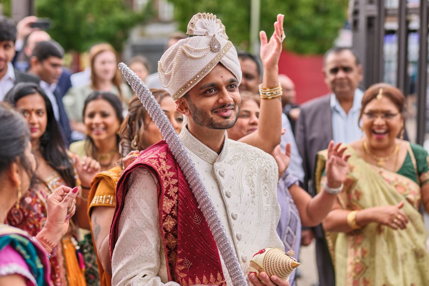 Joyful guests celebrate at a vibrant outdoor Indian wedding ceremony with colorful traditional attire.