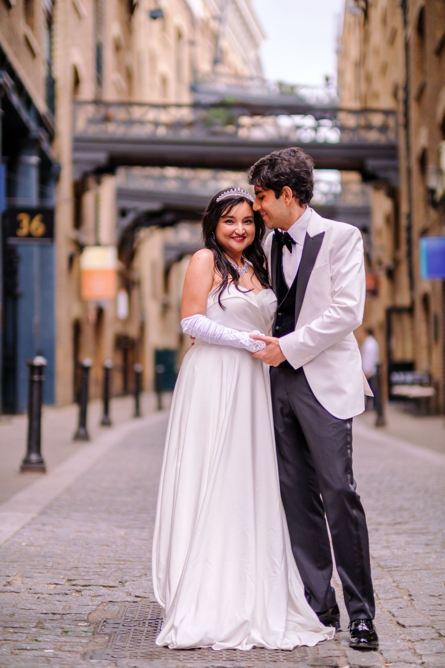 Wedding couple poses in a historic cobblestone alley with connecting bridges overhead.