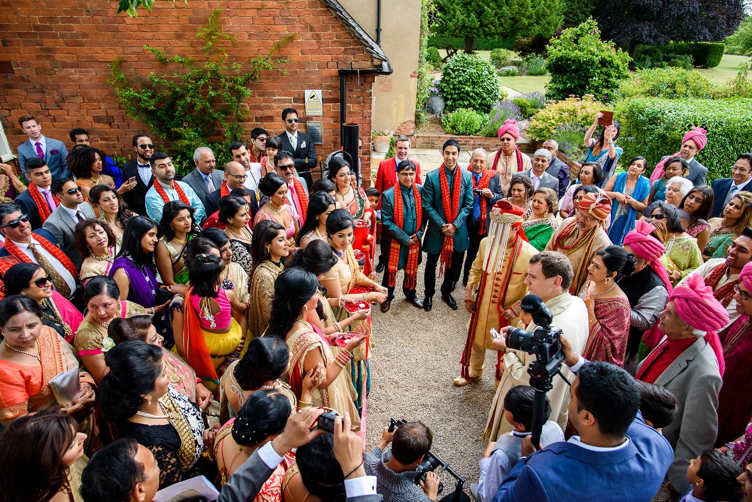 Colorfully dressed guests gather outside during festive Indian wedding celebration.