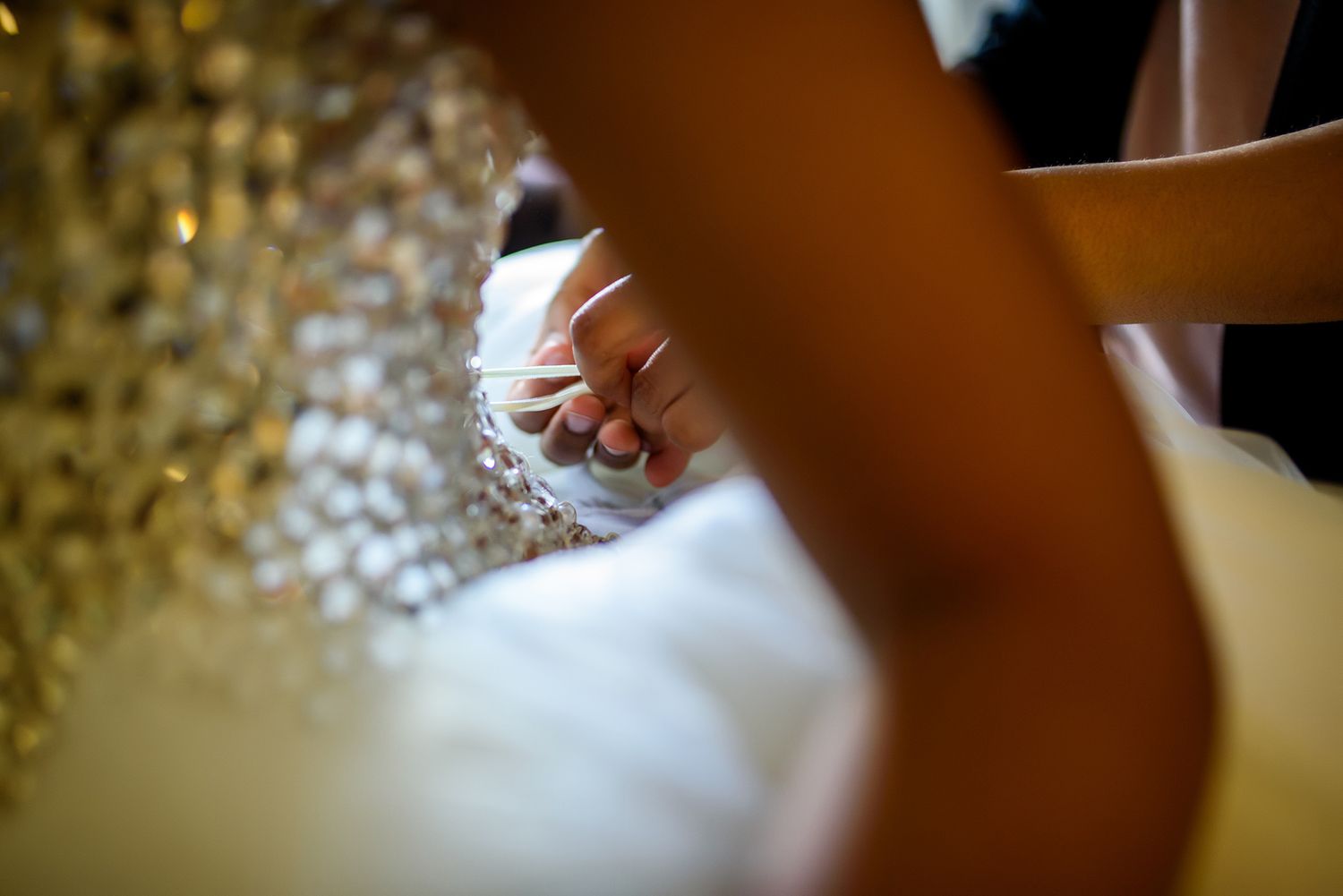 Close-up detail shot of wedding dress beading and crystals in soft focus.