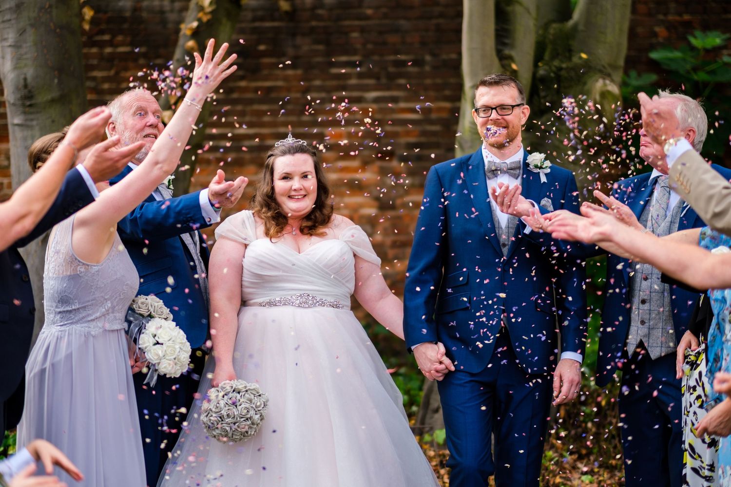 Wedding couple and guests celebrating with confetti outside venue.