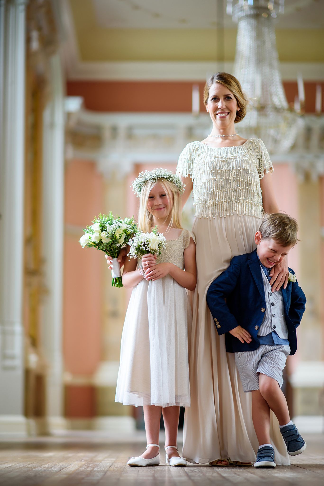 Wedding portrait showing attendants in white dresses and formal attire in an elegant venue.