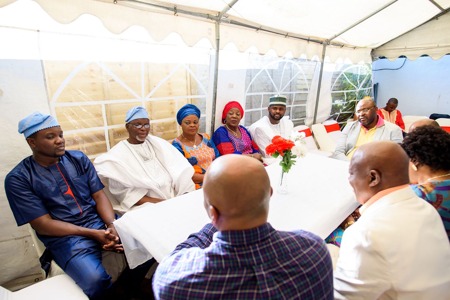 Group of attendees seated under a white tent during an outdoor event.