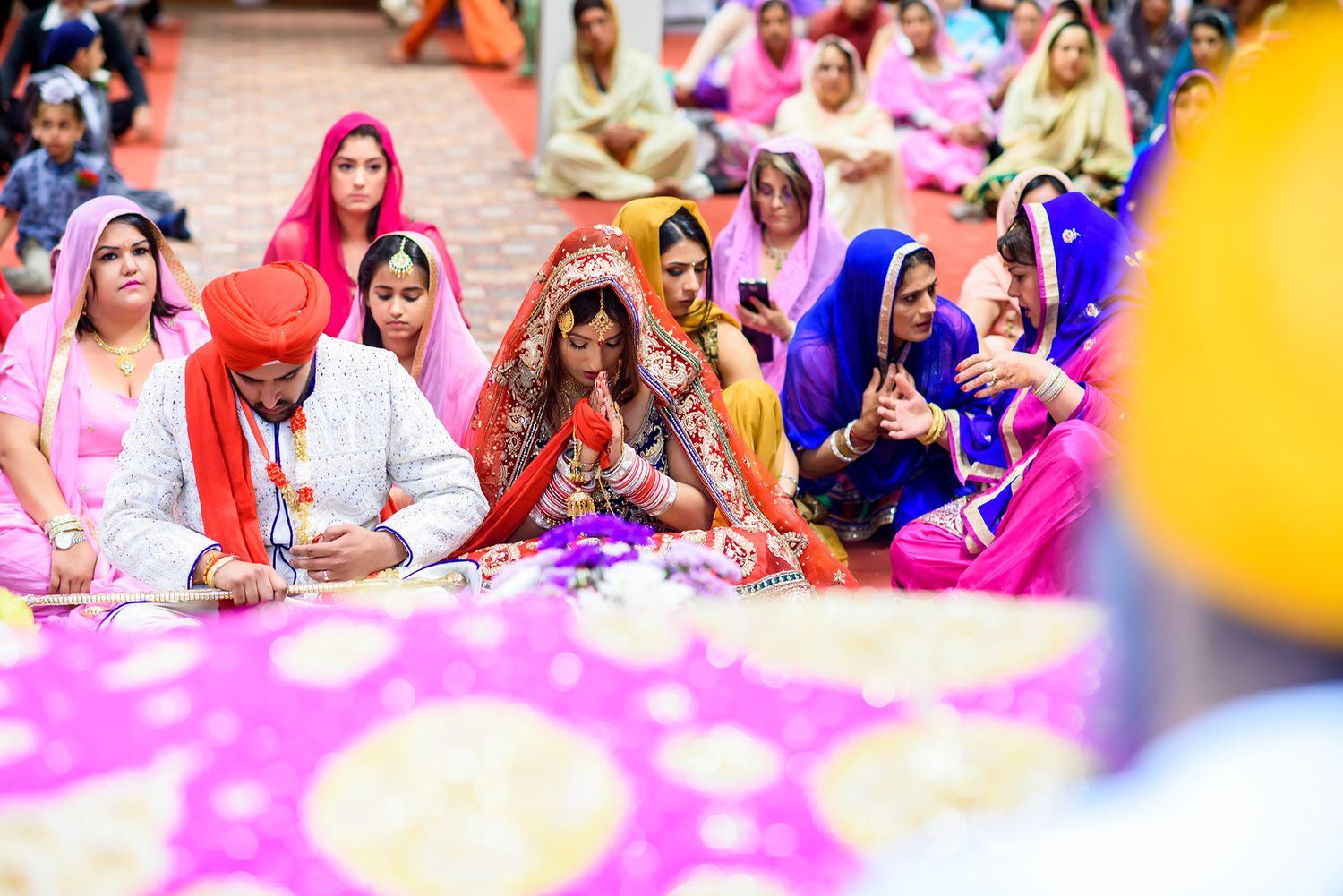 Guests in vibrant traditional attire seated during Sikh wedding celebration.