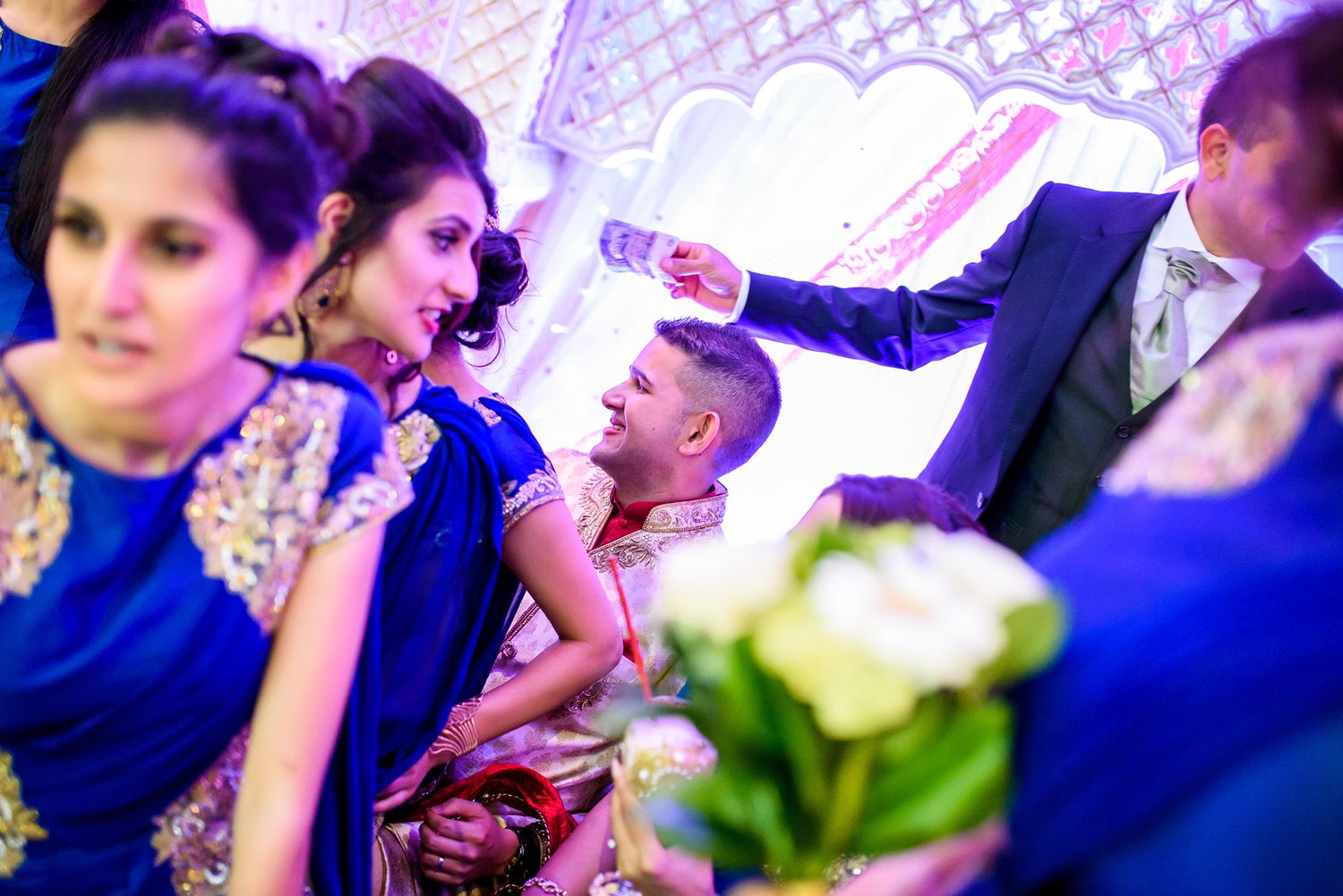 Lively wedding reception scene with guests dancing and celebrating under vibrant purple lighting.