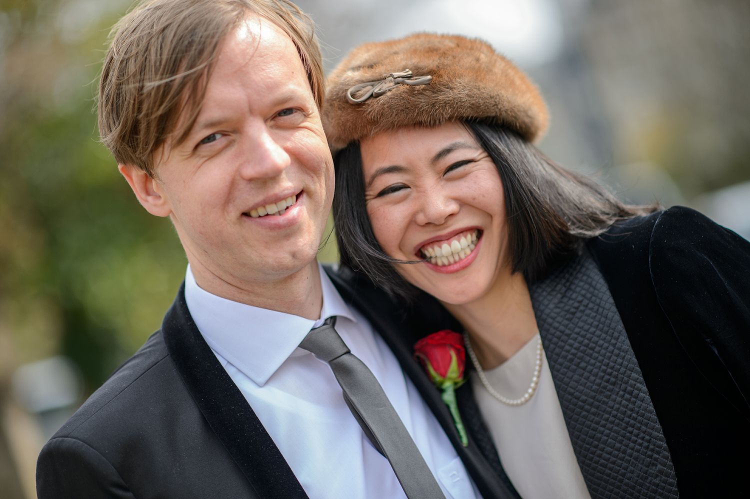 Couple in formal wear sharing a joyful moment outdoors.