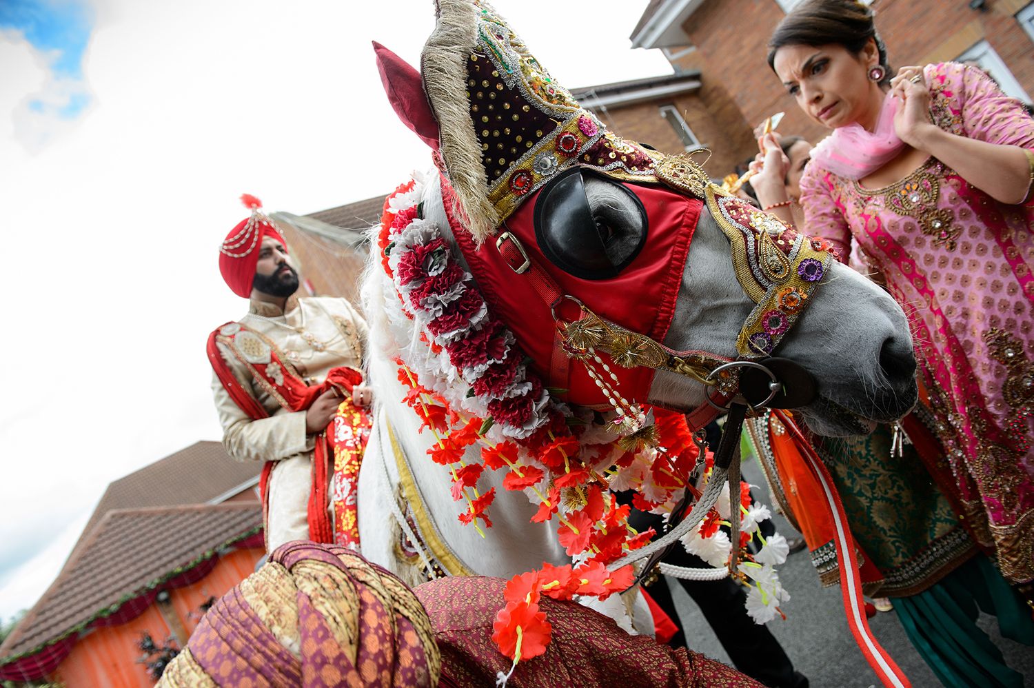 Colorful decorative Indian ceremonial horse head adorned with red and gold ornaments at a traditional celebration.