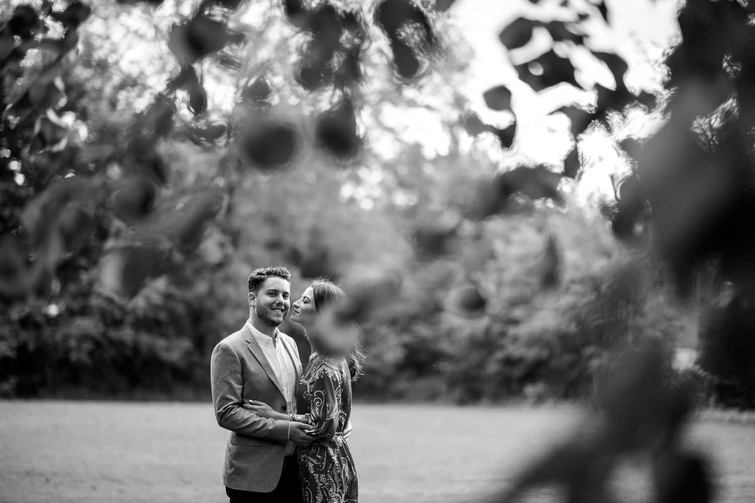 Black and white photos showing a couple embracing outdoors during a romantic photoshoot.