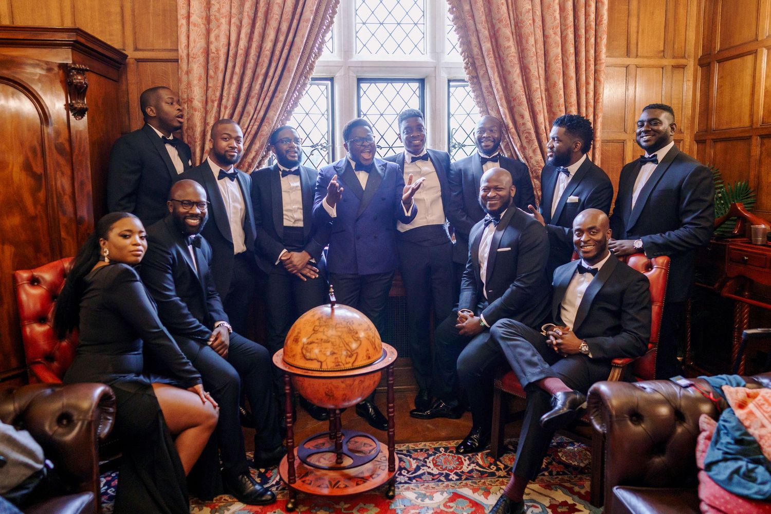 Wedding guests mingle and socialize in an elegant wood-paneled room with ornate architectural details.