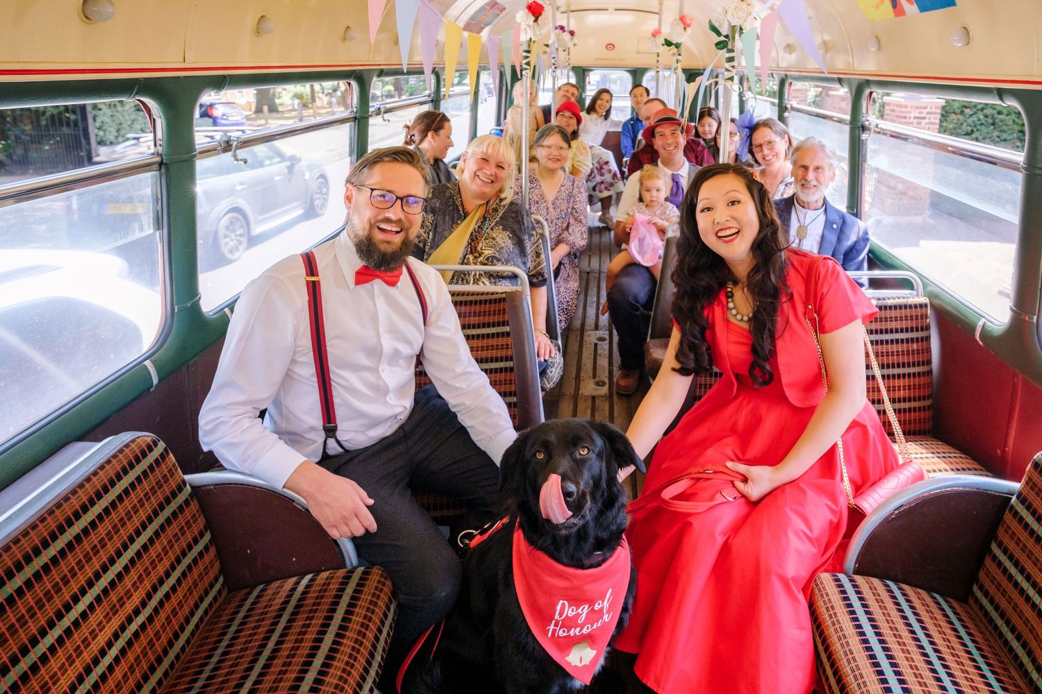Interior view of a classic London bus showing traditional patterned seats and passengers aboard.