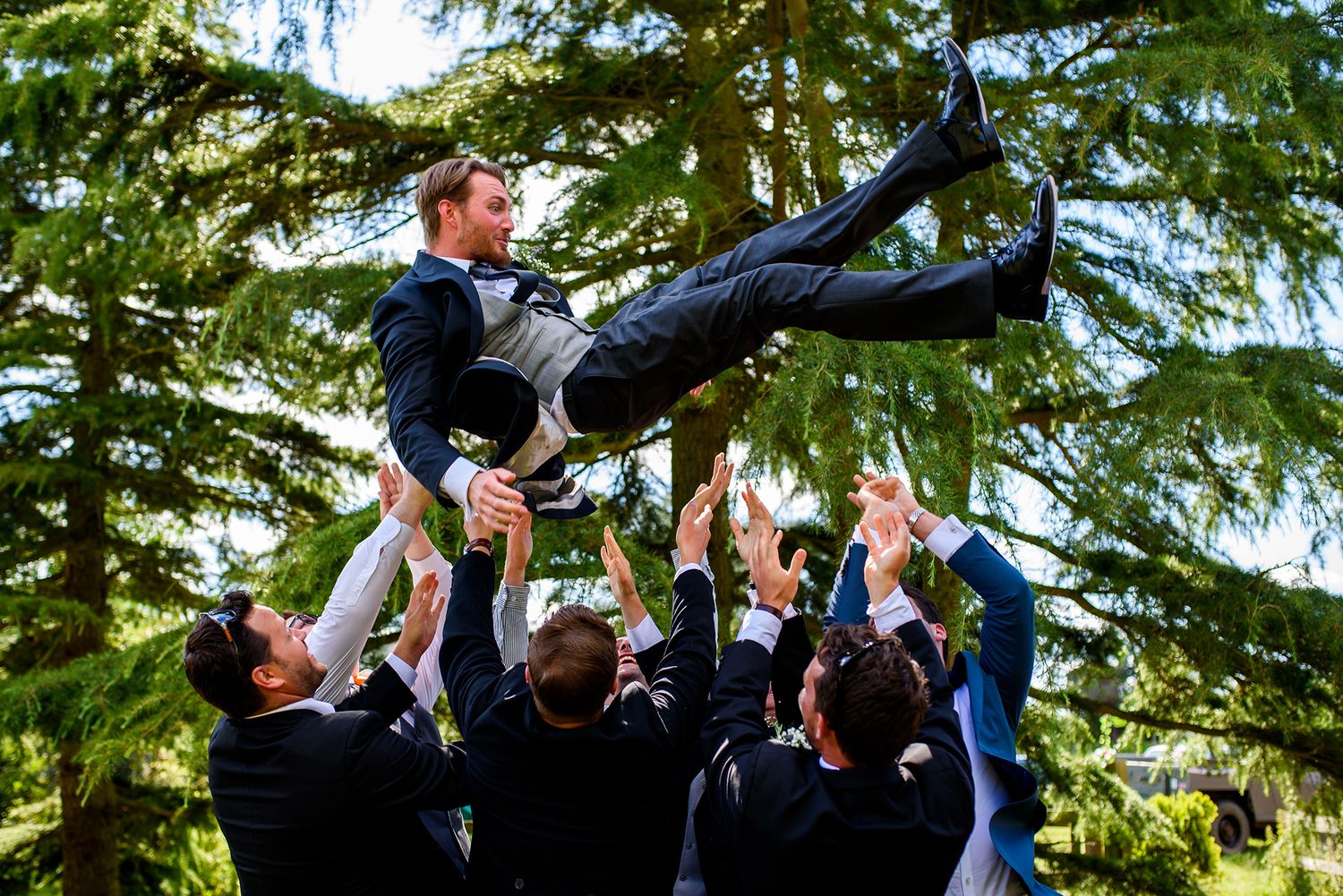 Groomsmen performing acrobatic group poses during outdoor wedding photo session.