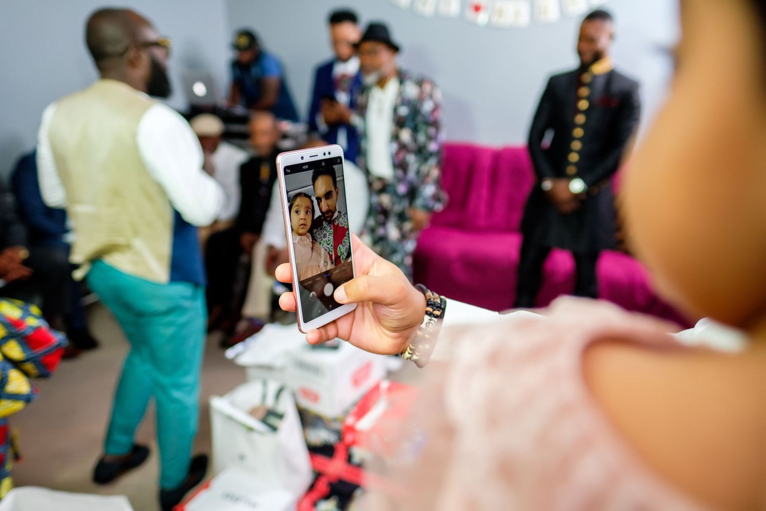 Colorful gathering of people enjoying a festive indoor celebration with mobile phones raised.