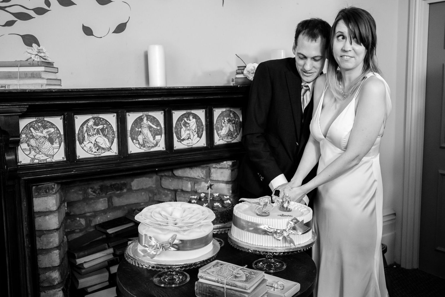 A couple cuts their wedding cake together in black and white photography.