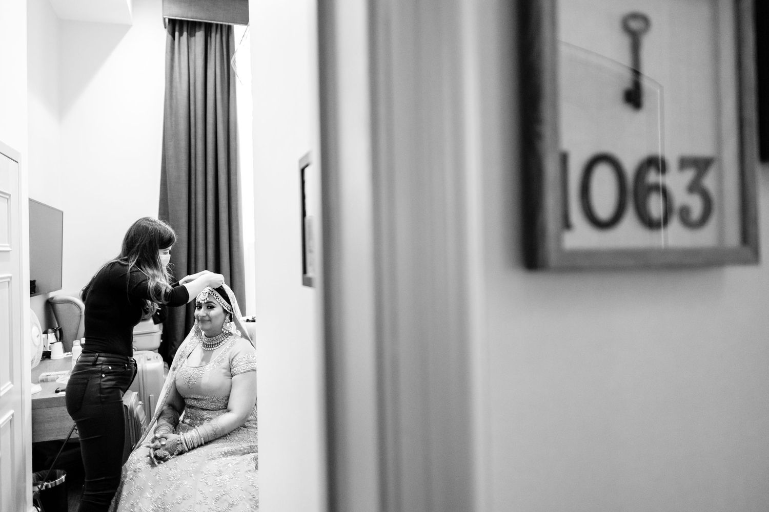 Black and white image showing hallway doors with room numbers in a hotel or apartment building.