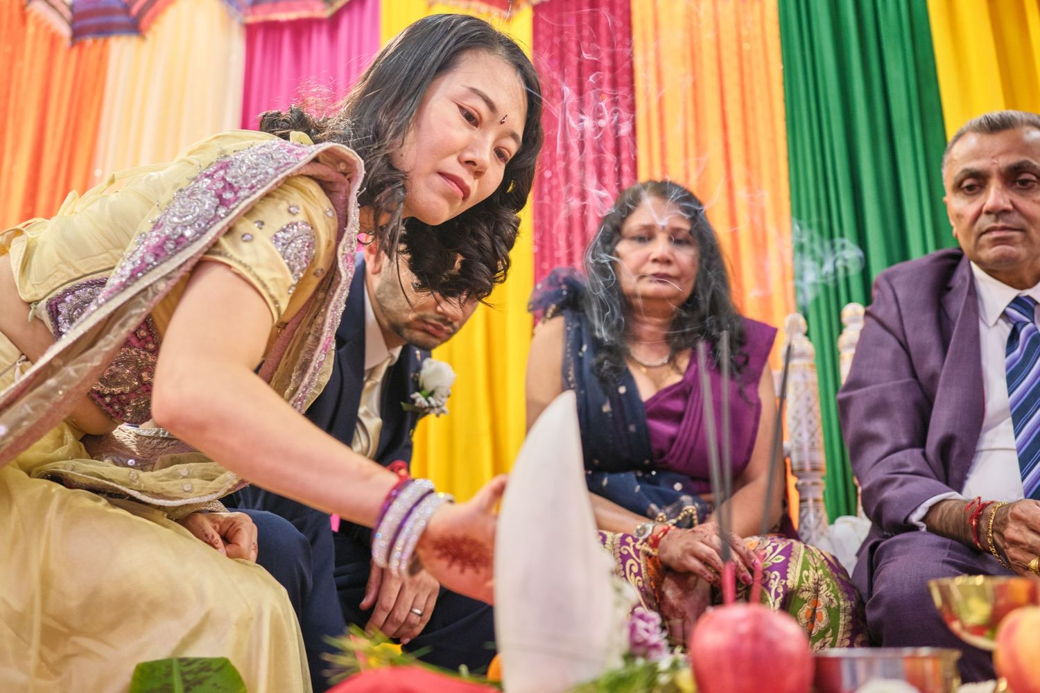 Colorful fabric backdrop in pink, green and yellow with people gathered at what appears to be a cultural celebration.