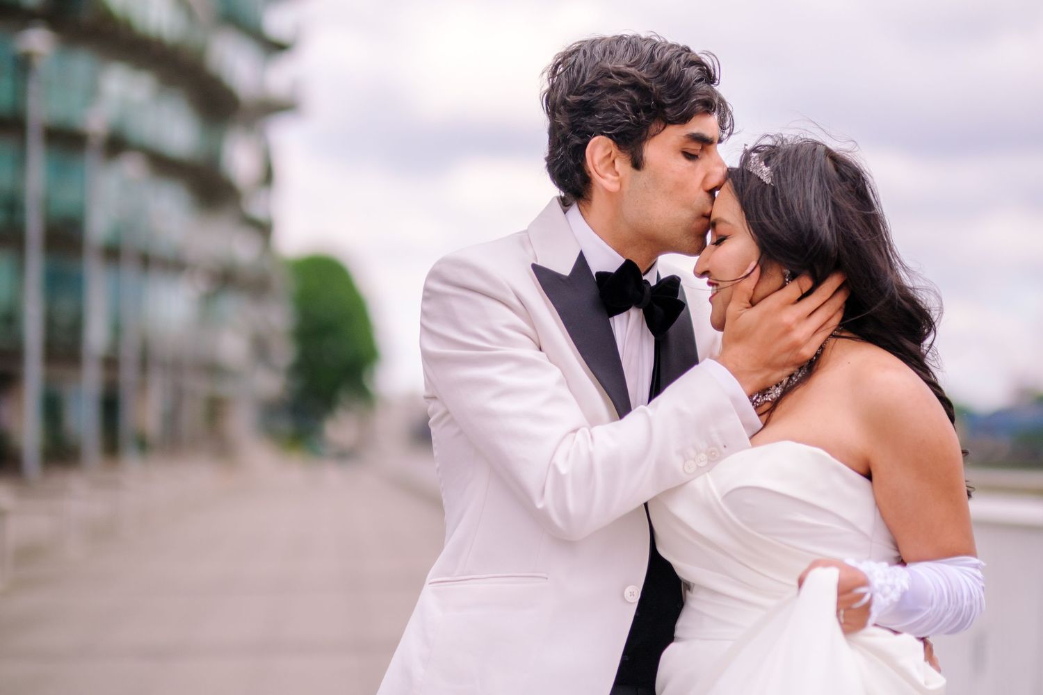 Romantic wedding couple sharing an intimate kiss against an urban backdrop.