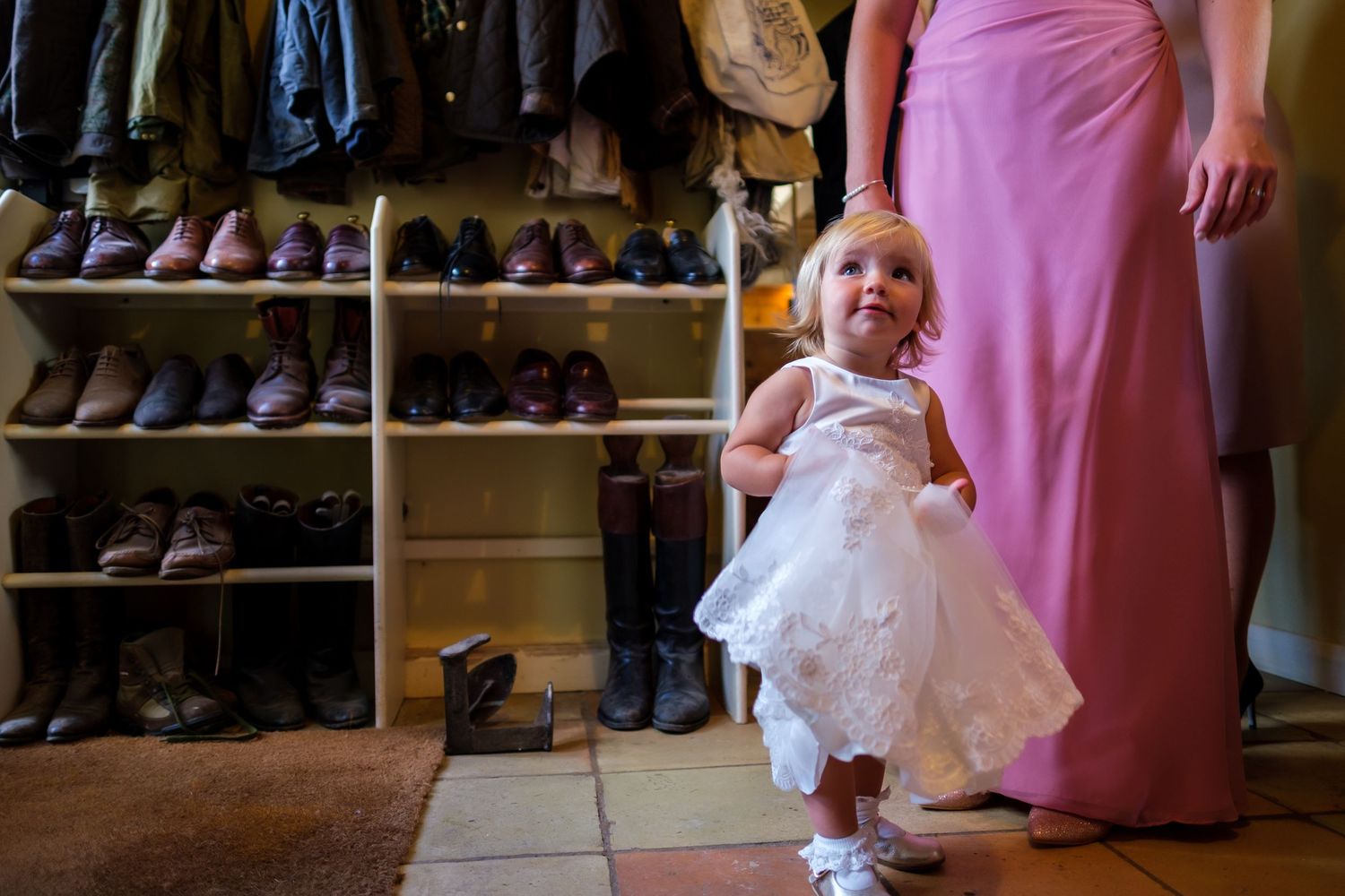 Pink bridesmaid dresses and formal shoes displayed in getting ready room.