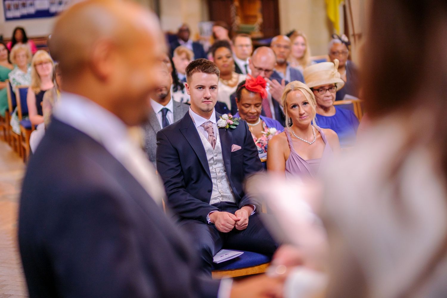 Wedding reception guests seated in rows at an indoor venue during a ceremony.