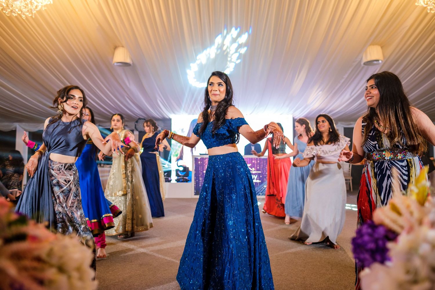 Wedding reception in an elegant white tent with guests dancing under draped fabric ceiling.