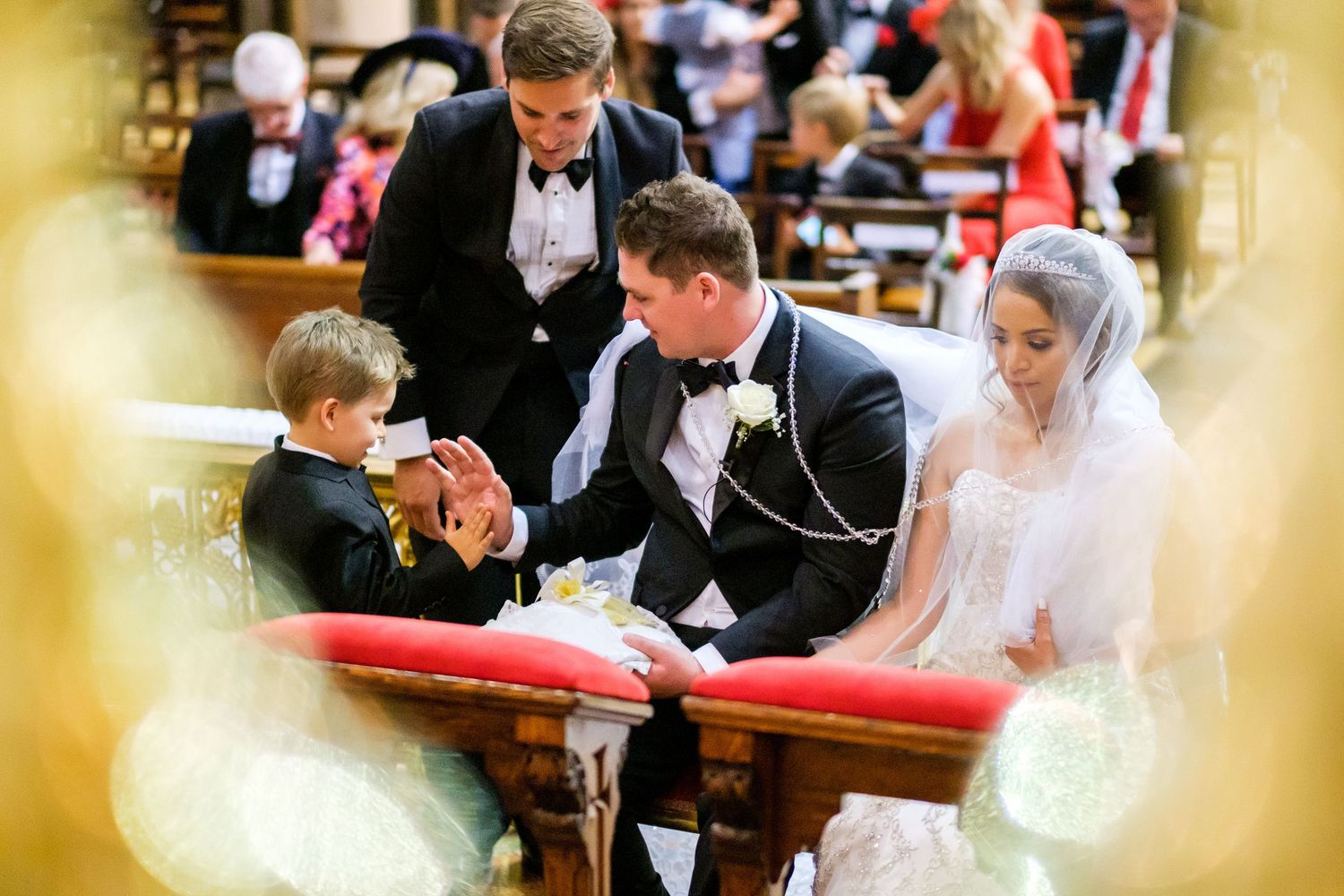 Intimate wedding ceremony moment in historic church with red carpet aisle.