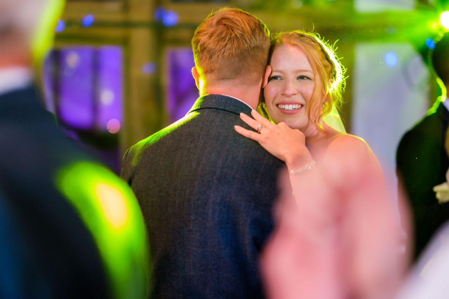 Dance floor moments captured with colorful purple lighting at wedding reception.