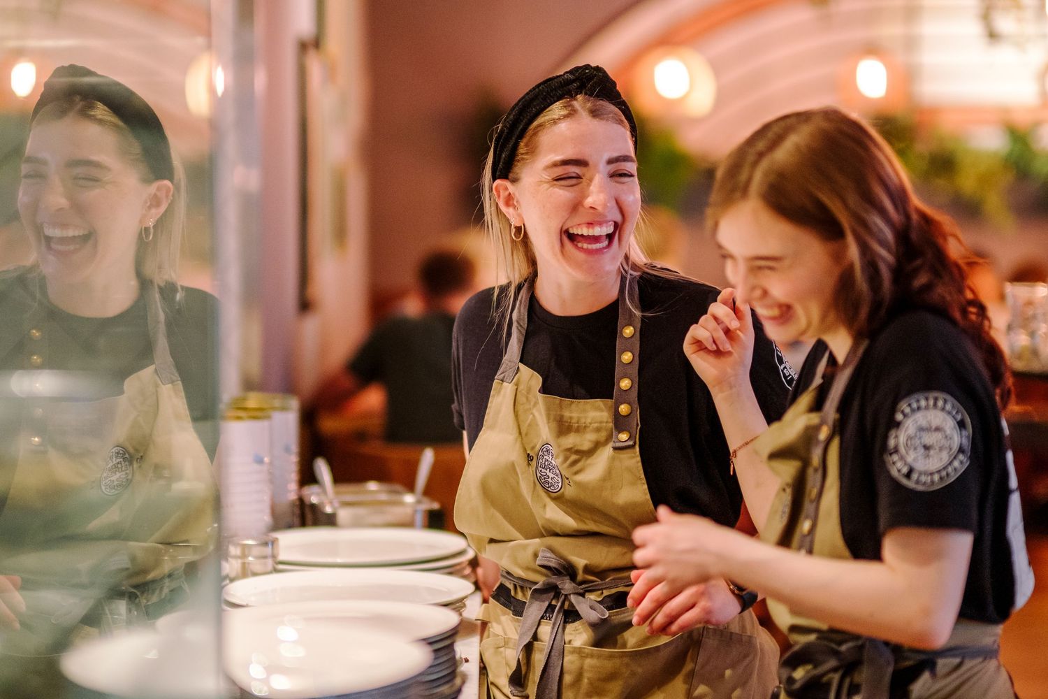 Lively restaurant scene with diners sharing conversation and laughter around tables.