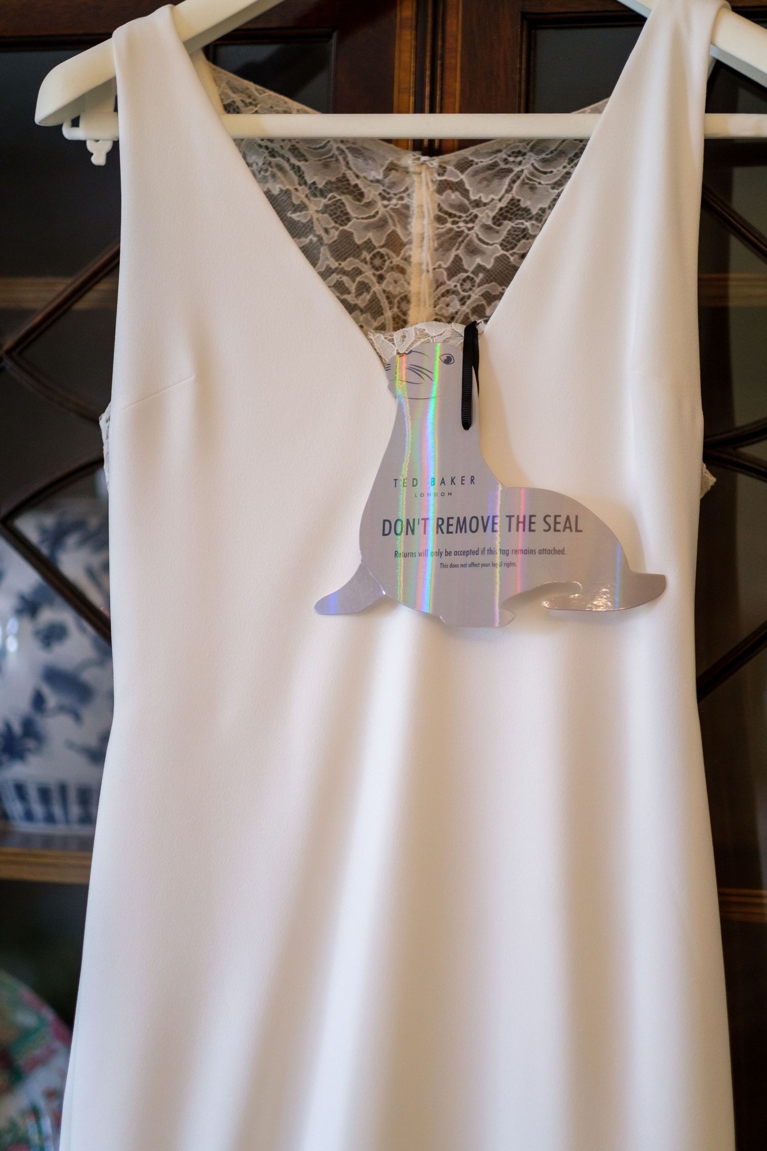 White wedding dress hanging on display shows elegant details and care instructions.