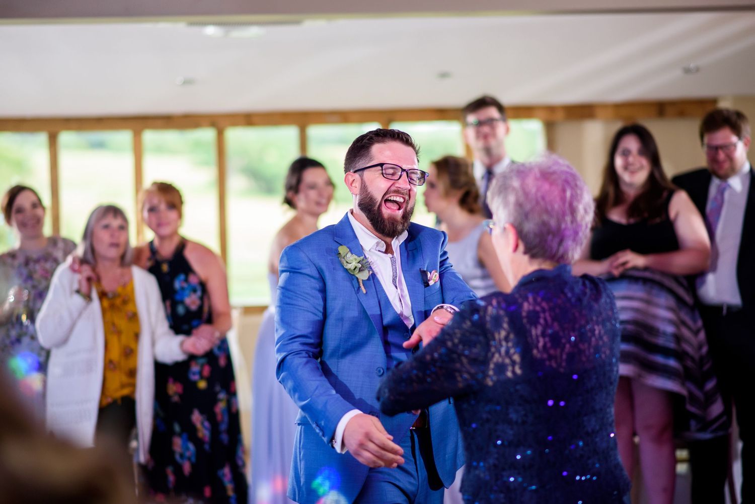Wedding guests dancing and celebrating on a dimly lit dance floor.