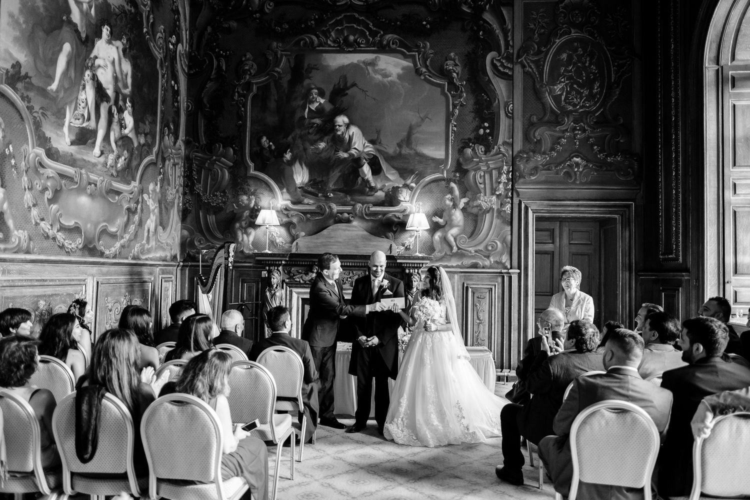 Wedding ceremony in a grand ornate ballroom with classical architecture and painted ceiling murals.