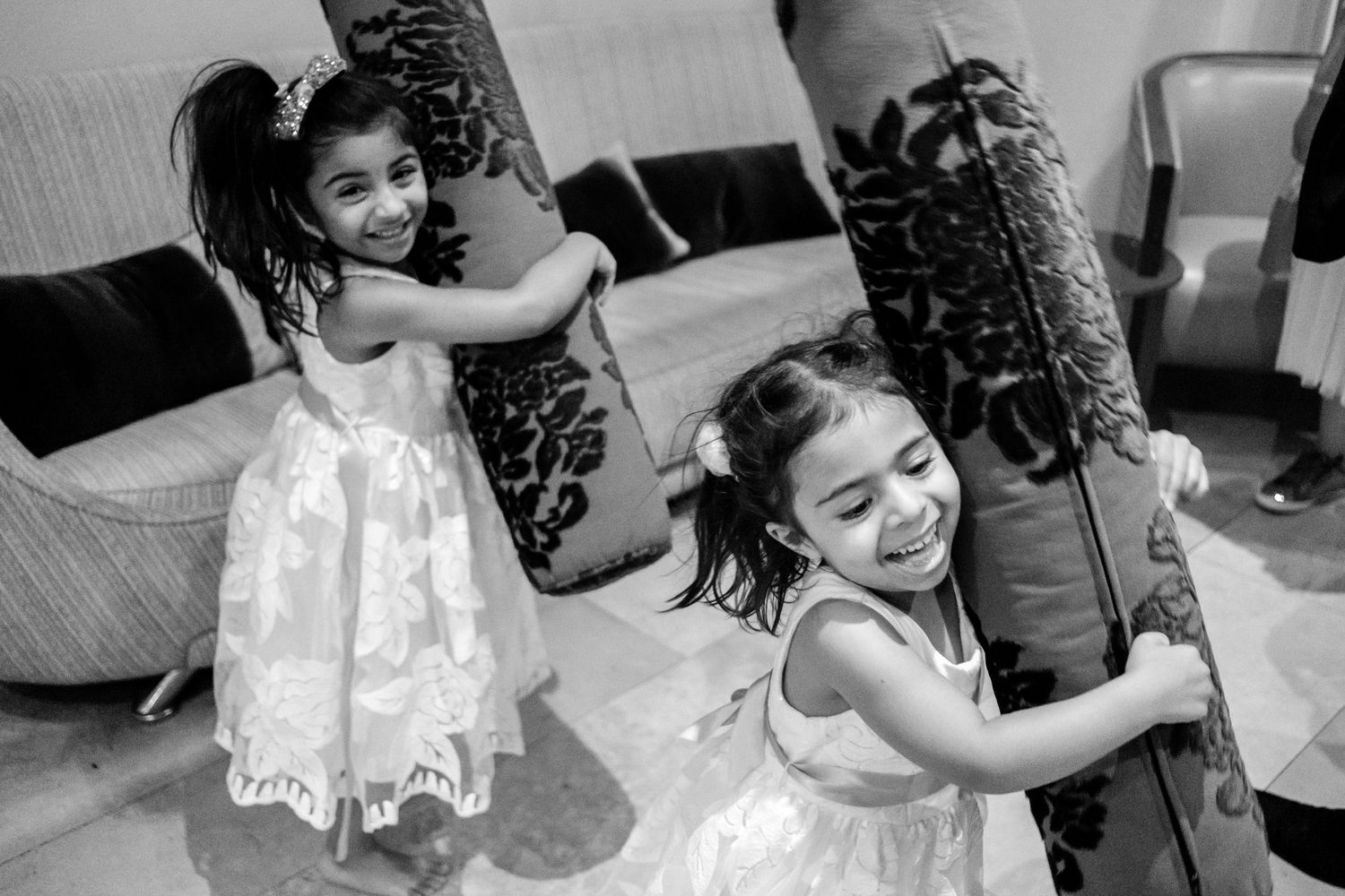 Young flower girls in white dresses dancing and twirling at a wedding celebration.