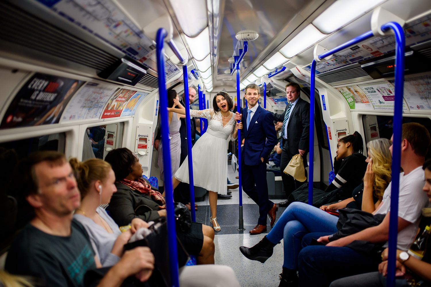 Interior view of a London Underground train carriage with blue seats and passengers.