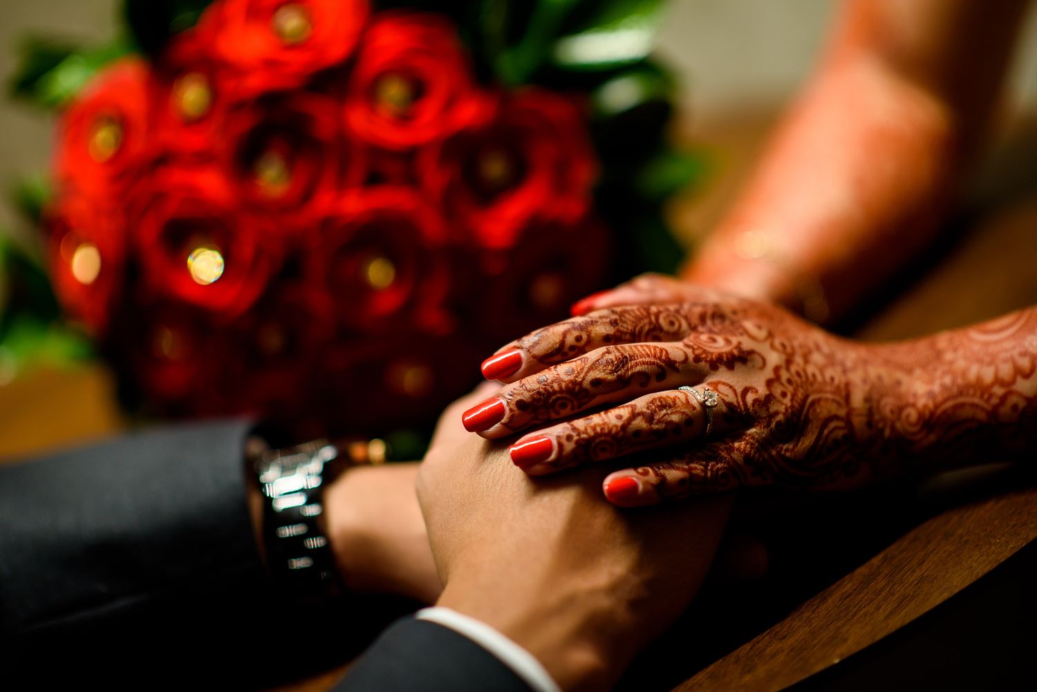 Close-up of intricate henna designs with vibrant red roses as decoration.