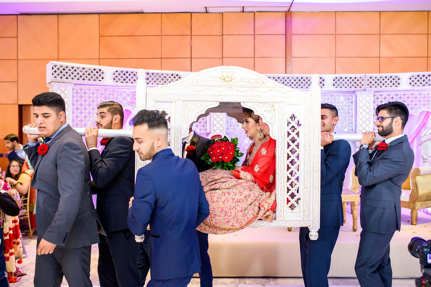 Wedding party members in navy suits sharing moments at reception venue.