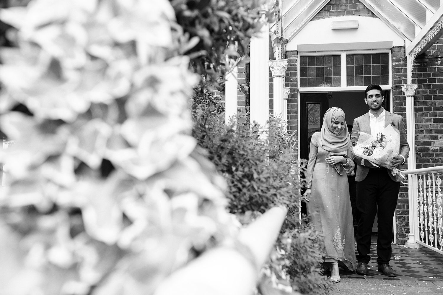Couple walking together on a garden path near a house.