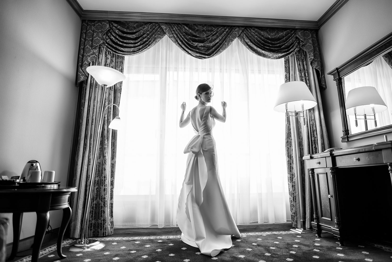 Elegant white curtained room showing silhouettes and reflections in classic wedding preparation setting.