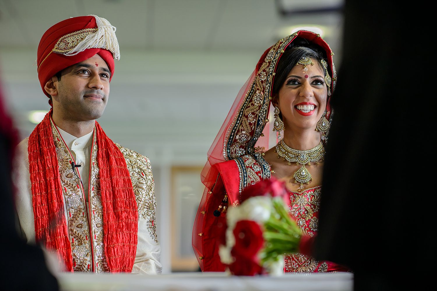 Traditional Indian wedding ceremony with couple in red and gold attire during rituals.