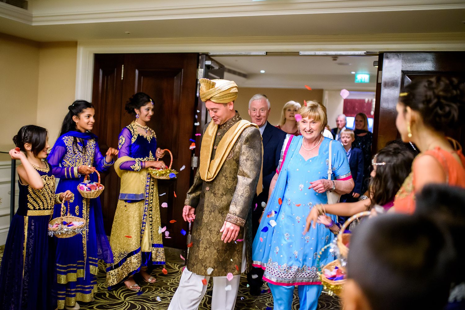 Wide panoramic shot of a wedding celebration in a luxurious ballroom setting.