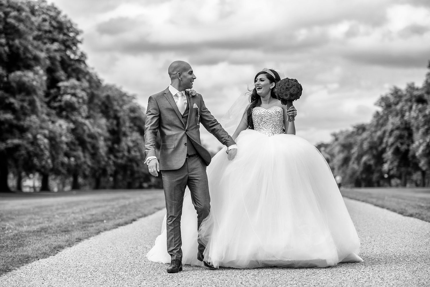 Creative black and white wedding portrait on grassy hillside.