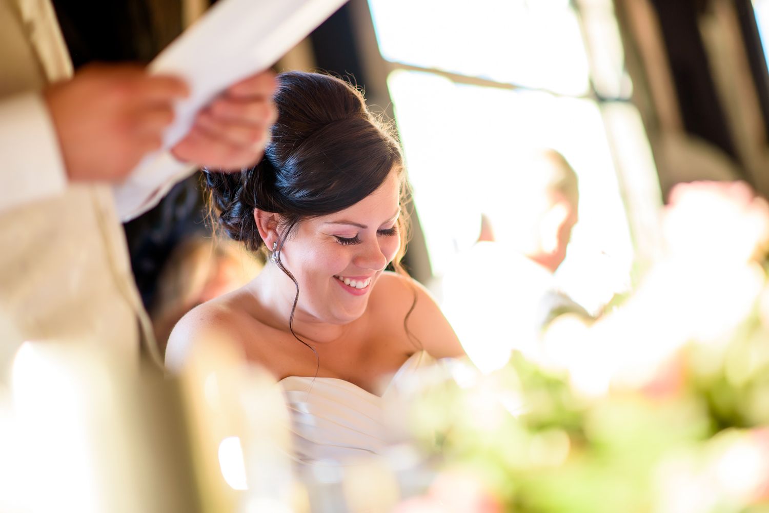 A joyful moment during a wedding reception as the couple listens to speeches and toasts.
