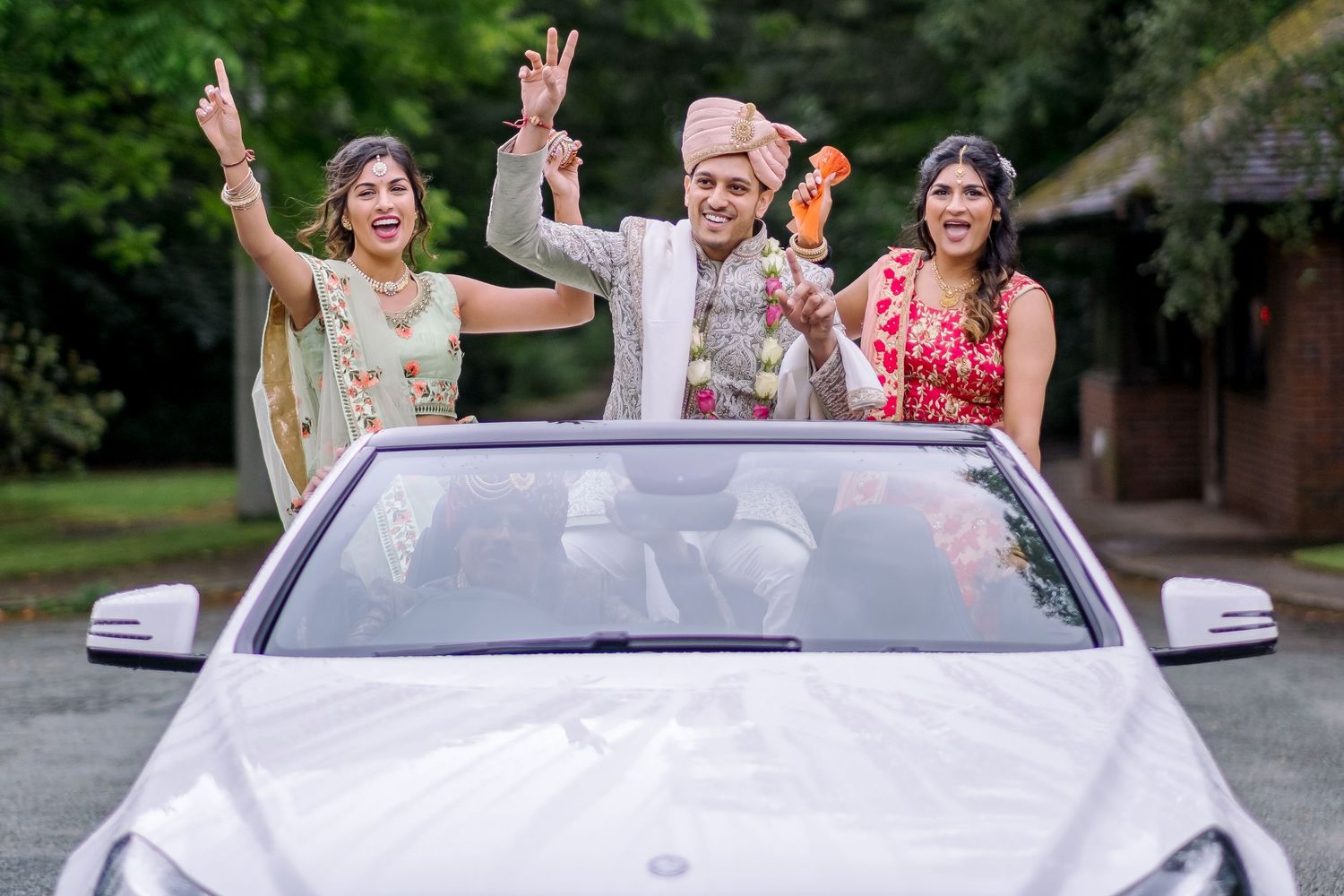 Wedding party celebrating with colorful smoke bombs in an outdoor garden setting.