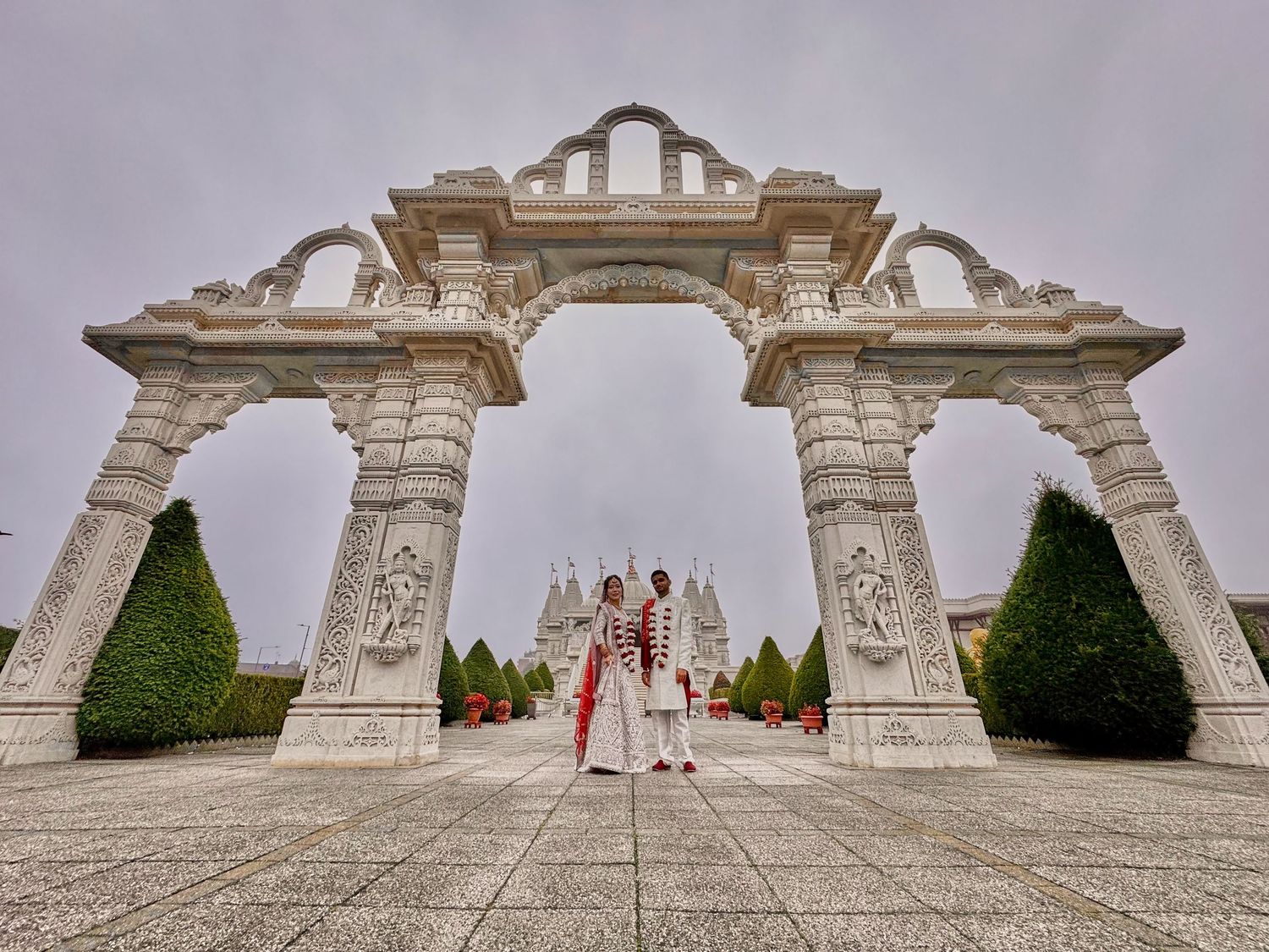 Wide angle shot of white marble archways and decorative gates at BAPS Swaminarayan Mandir temple grounds.