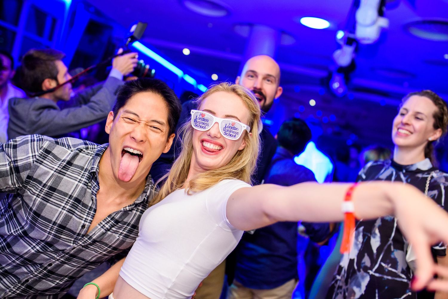 Party scene with blue lighting and people dancing and celebrating.
