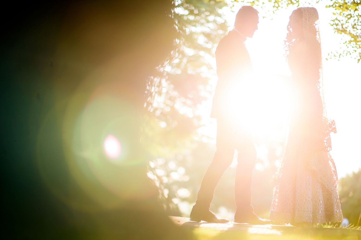 Golden sunlight flares create dreamy atmosphere in outdoor portrait session.