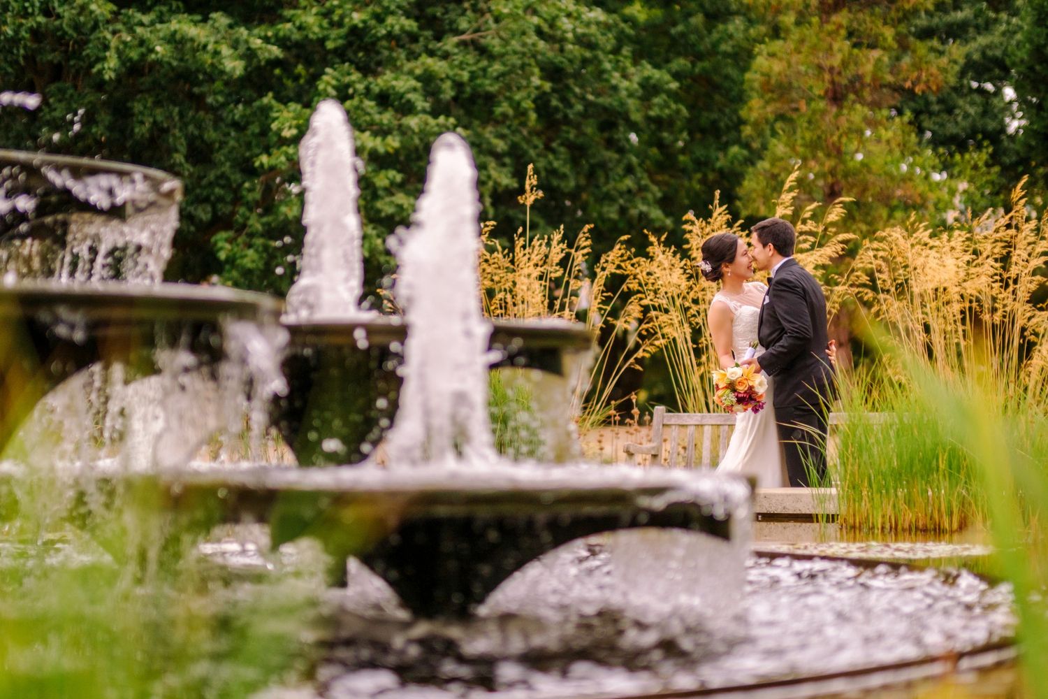 Stone fountain in a garden with tall grass and trees creating a peaceful outdoor setting.