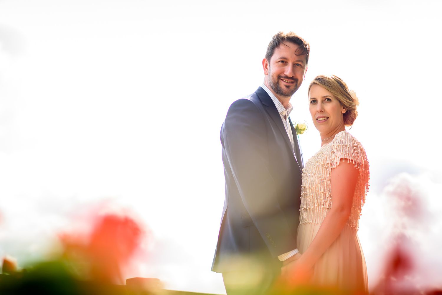 Intimate wedding couple portraits with soft focus flowers in foreground.