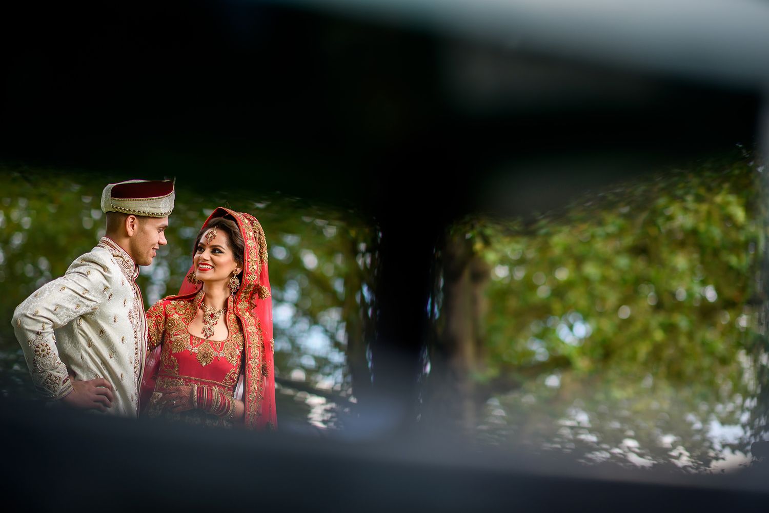Candid outdoor wedding portrait captured through natural elements.