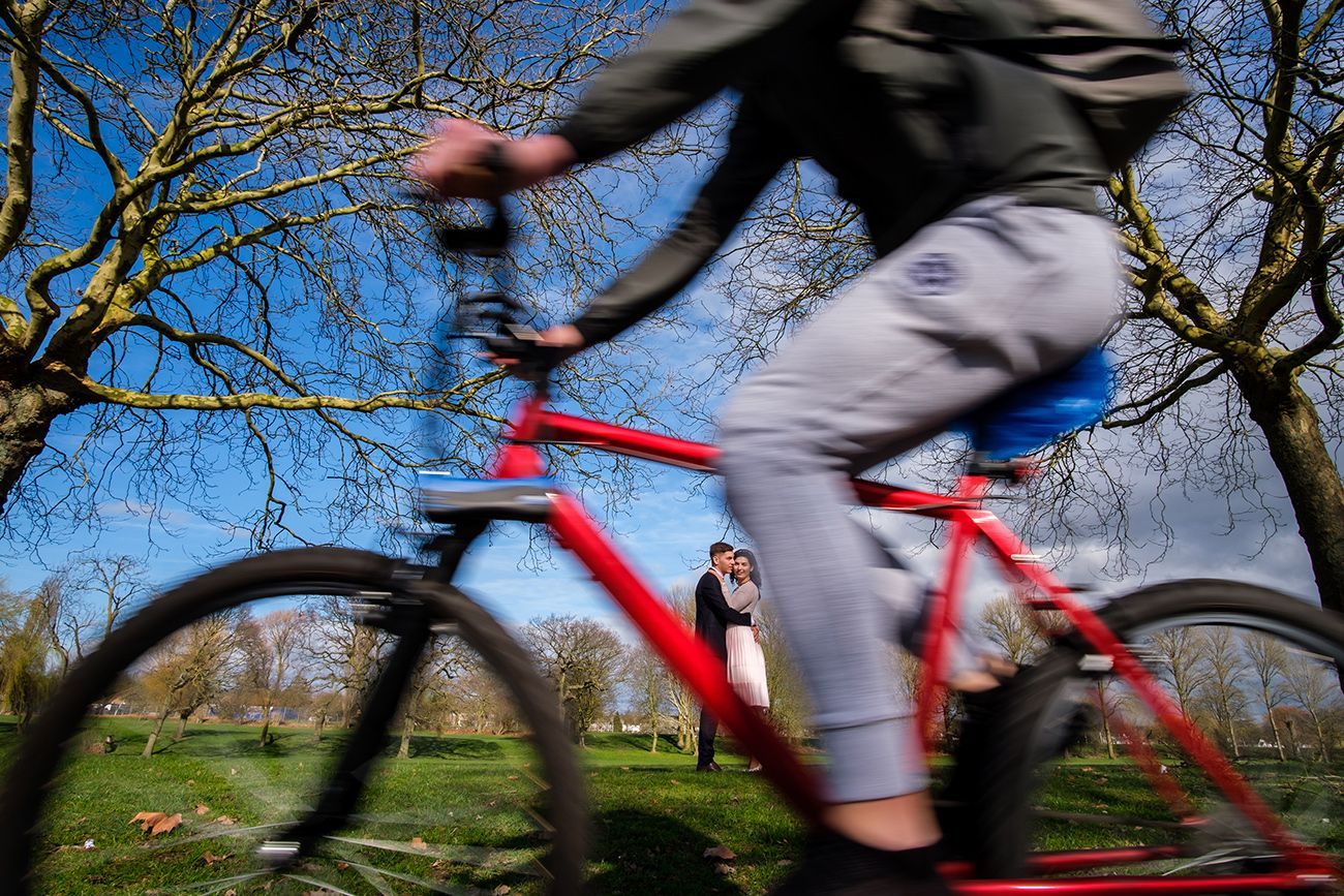 Motion blur of cyclists riding past trees in a park on a sunny day.